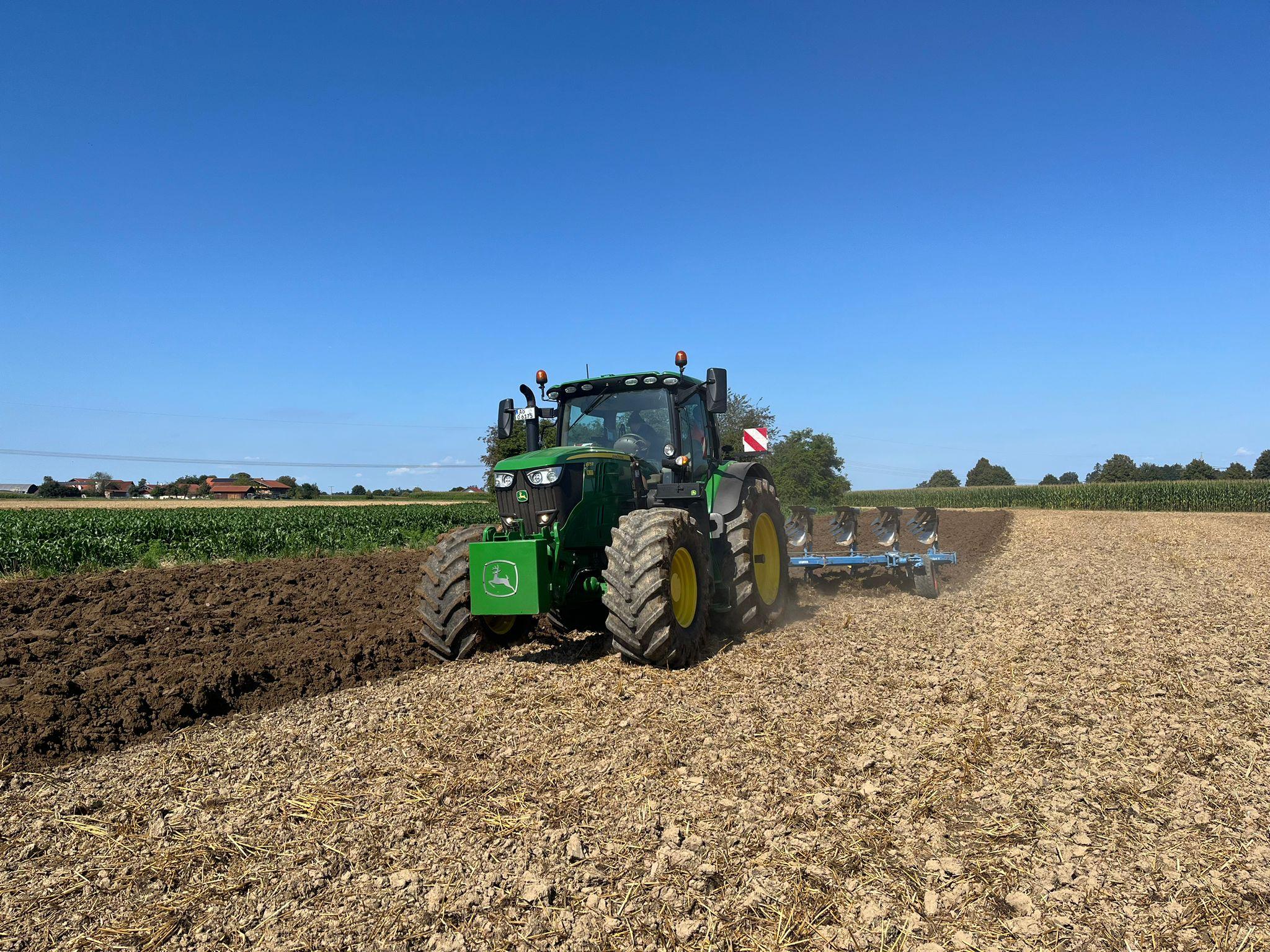 John Deere Traktor bei der Bodenbearbeitung mit Pflug auf einem Acker – professionelle landwirtschaftliche Dienstleistungen von Ostermaier.