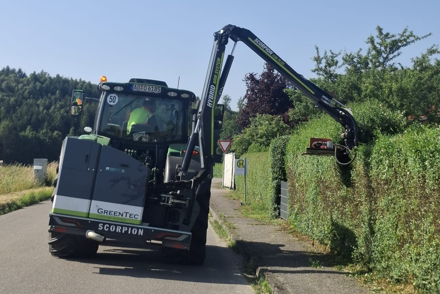 Moderne Maschine von Ostermaier Dienstleistungen bei der professionellen Heckenpflege am Straßenrand – umwelttechnische Dienstleistungen für gepflegte Grünanlagen.